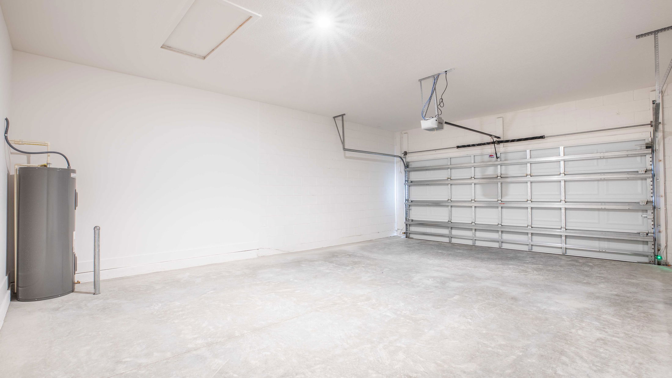 Empty residential garage interior with concrete floor and large closed garage door.