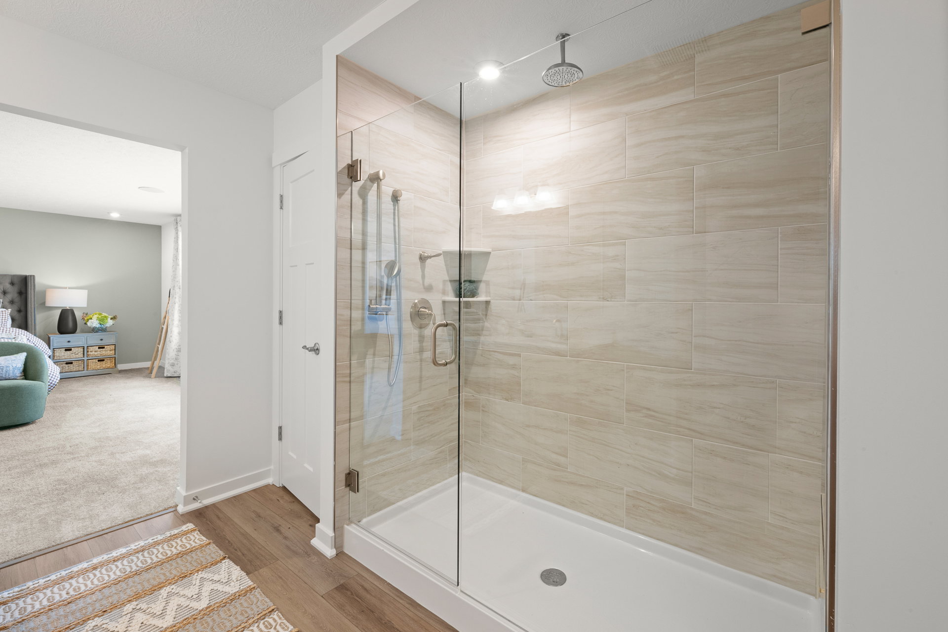 Modern tiled shower enclosure with glass walls and a silver showerhead.