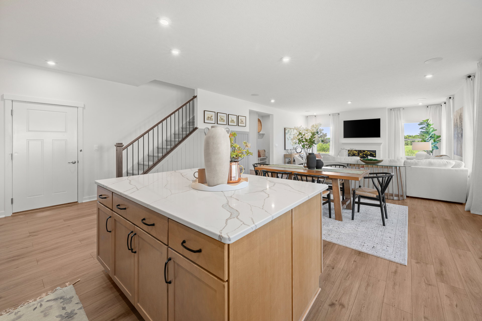 Bright, modern living space featuring a kitchen island, dining table, and a cozy seating area with large windows.