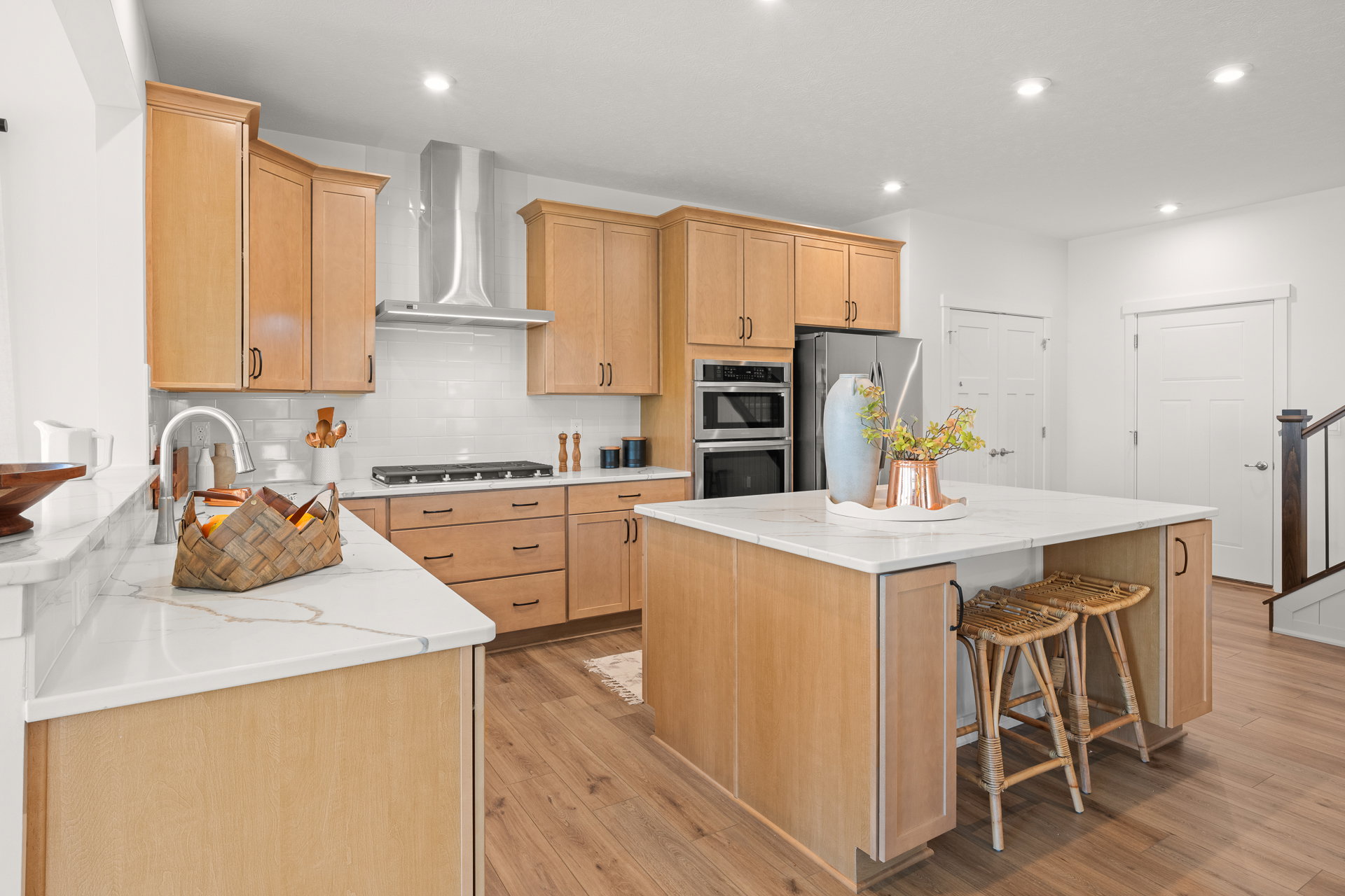 Modern kitchen with wooden cabinets, stainless steel appliances, and a large island with bar stools.