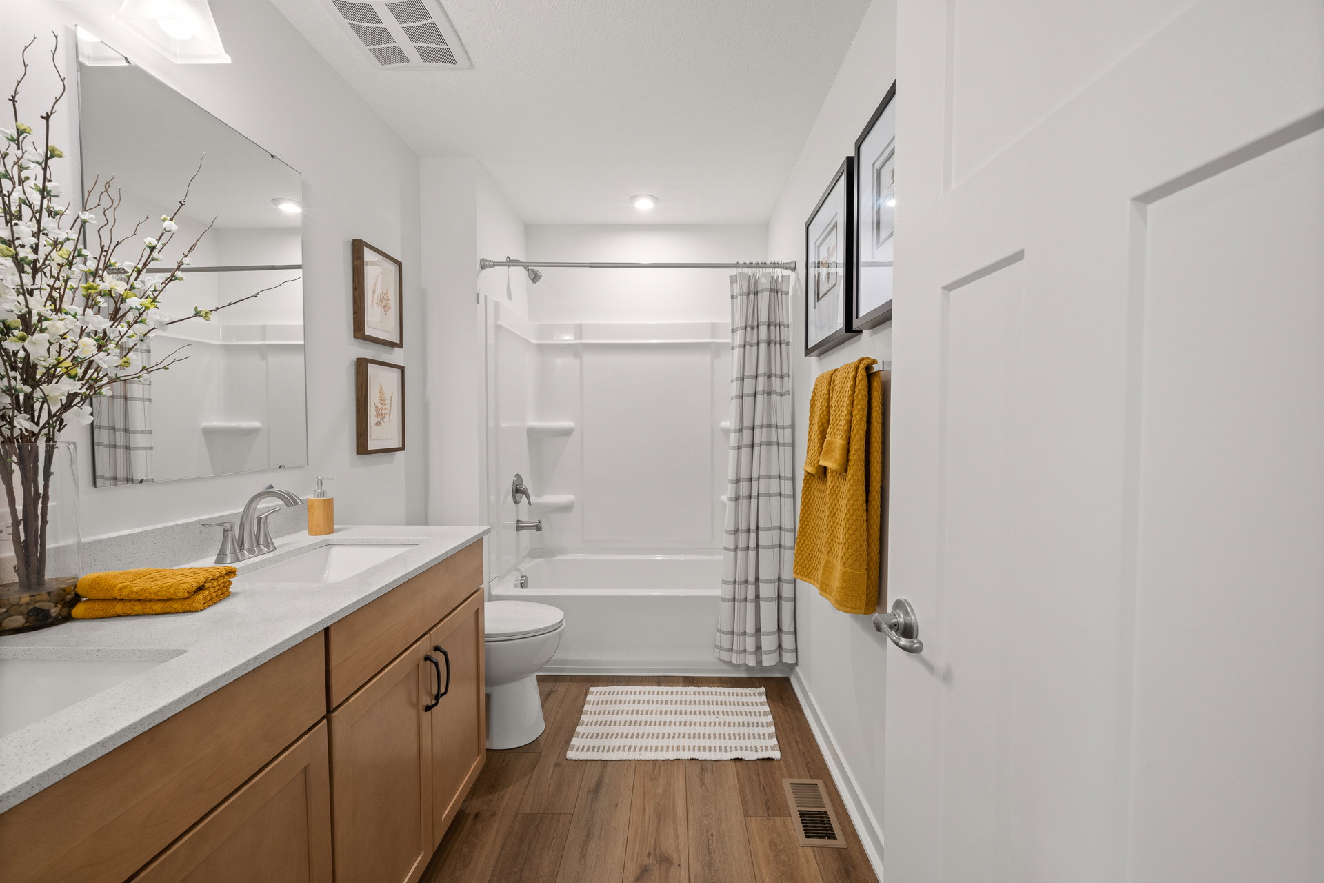 Bright and modern bathroom featuring a white countertop, wooden cabinets, and a shower with a curtain.