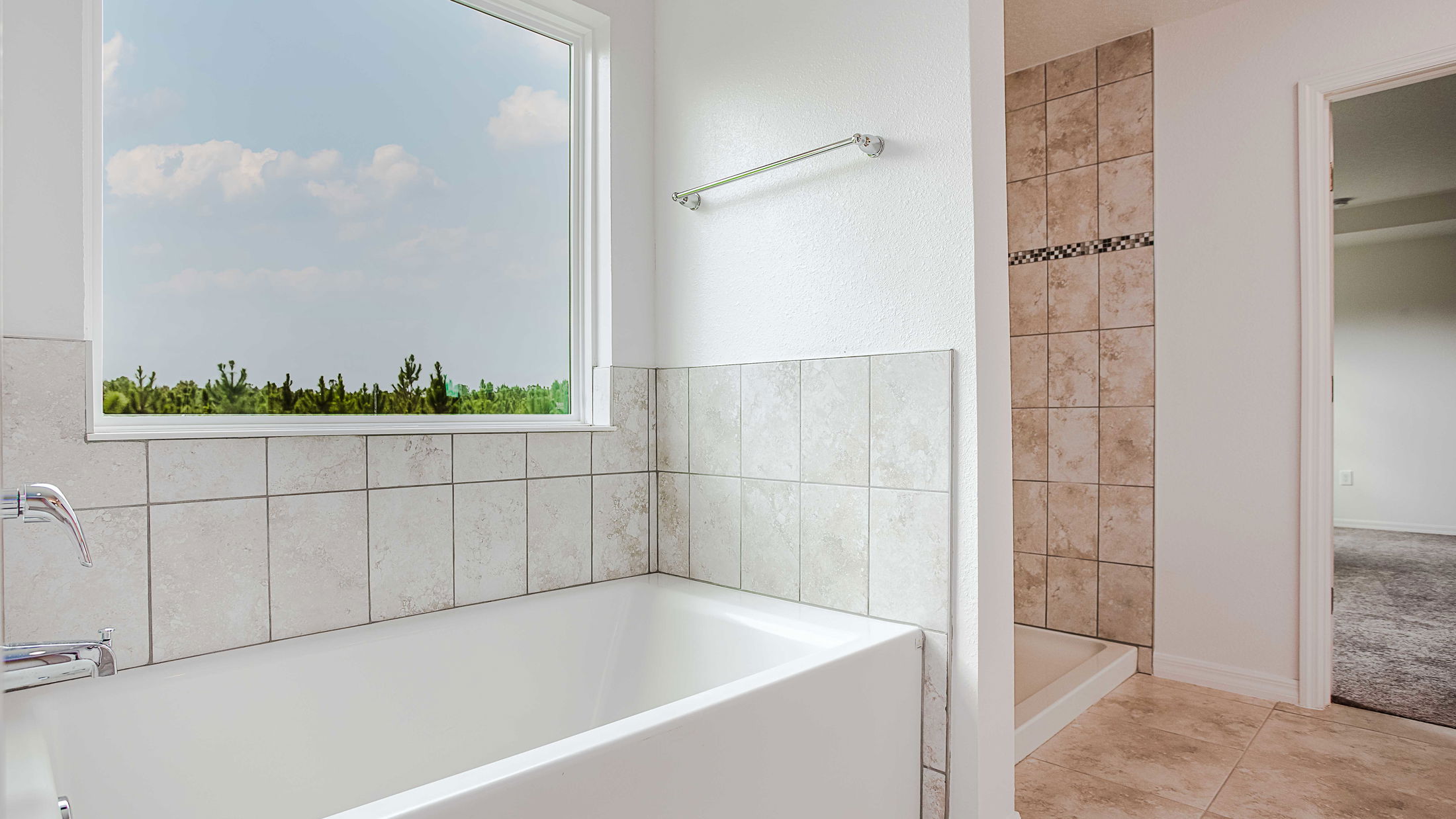 Modern bathroom featuring a spacious tub, elegant tile design, and a large window with a scenic view.