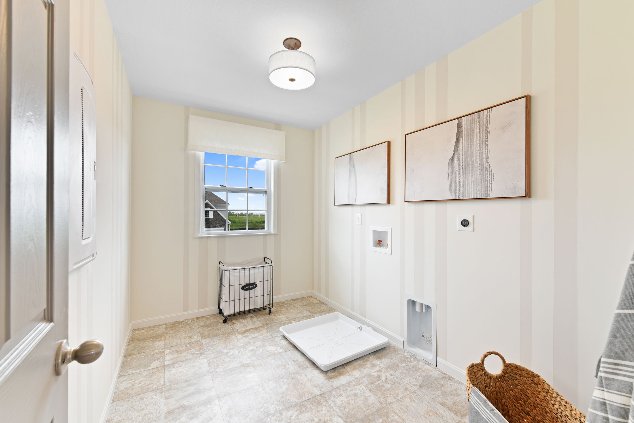 Bright and modern laundry room with tiled floor, window view, and wall art.
