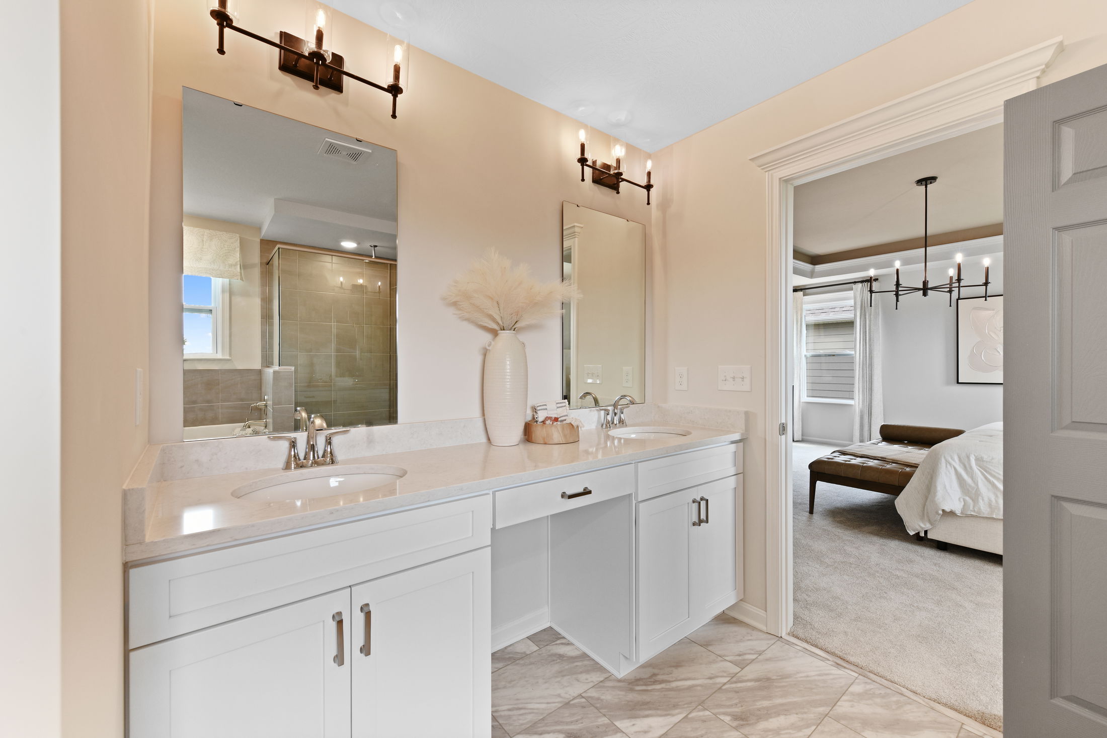 Elegant modern bathroom with double vanity, marble countertops, and view into a stylish bedroom.