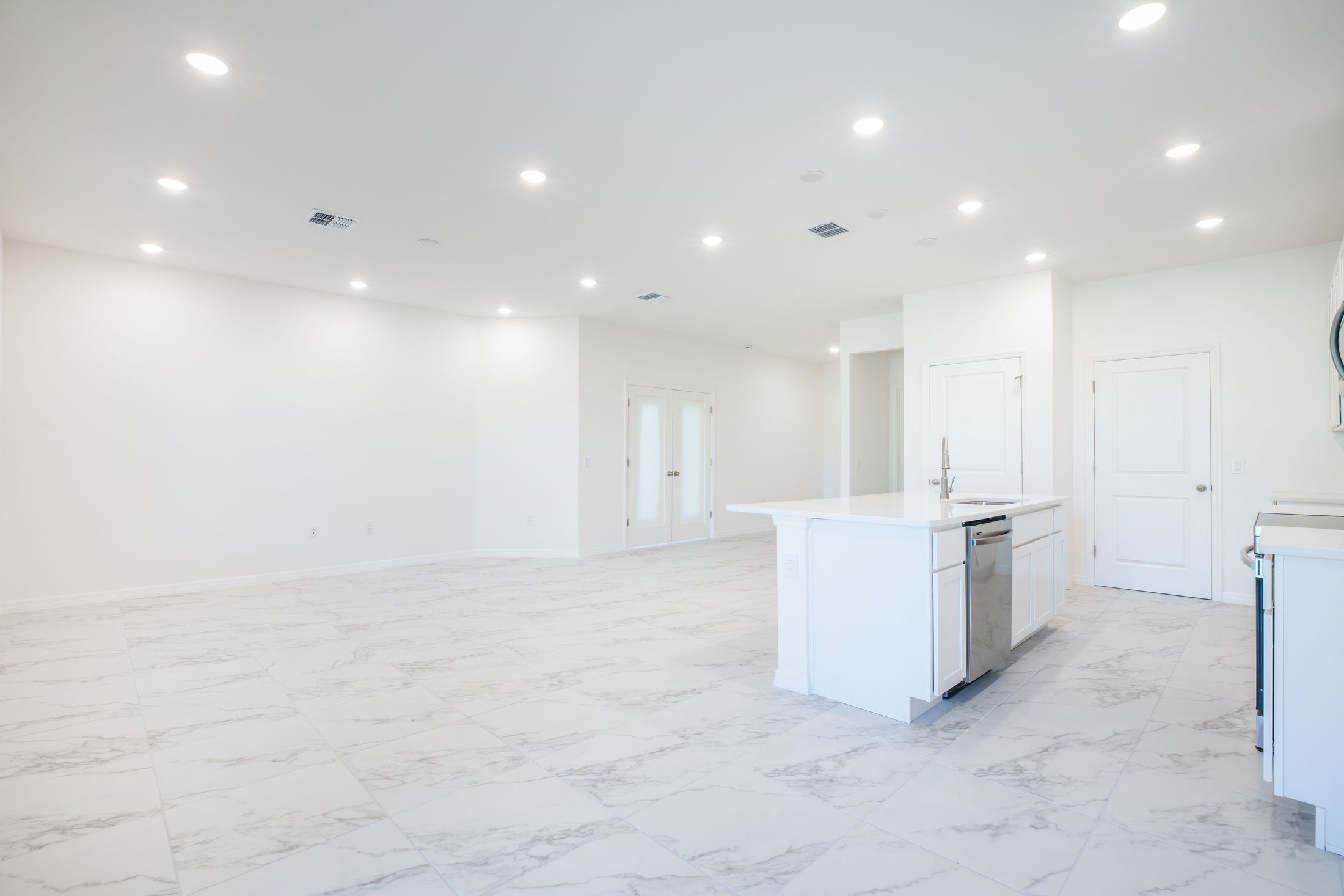 Modern open-concept kitchen and living area with white marble tiles and island counter.