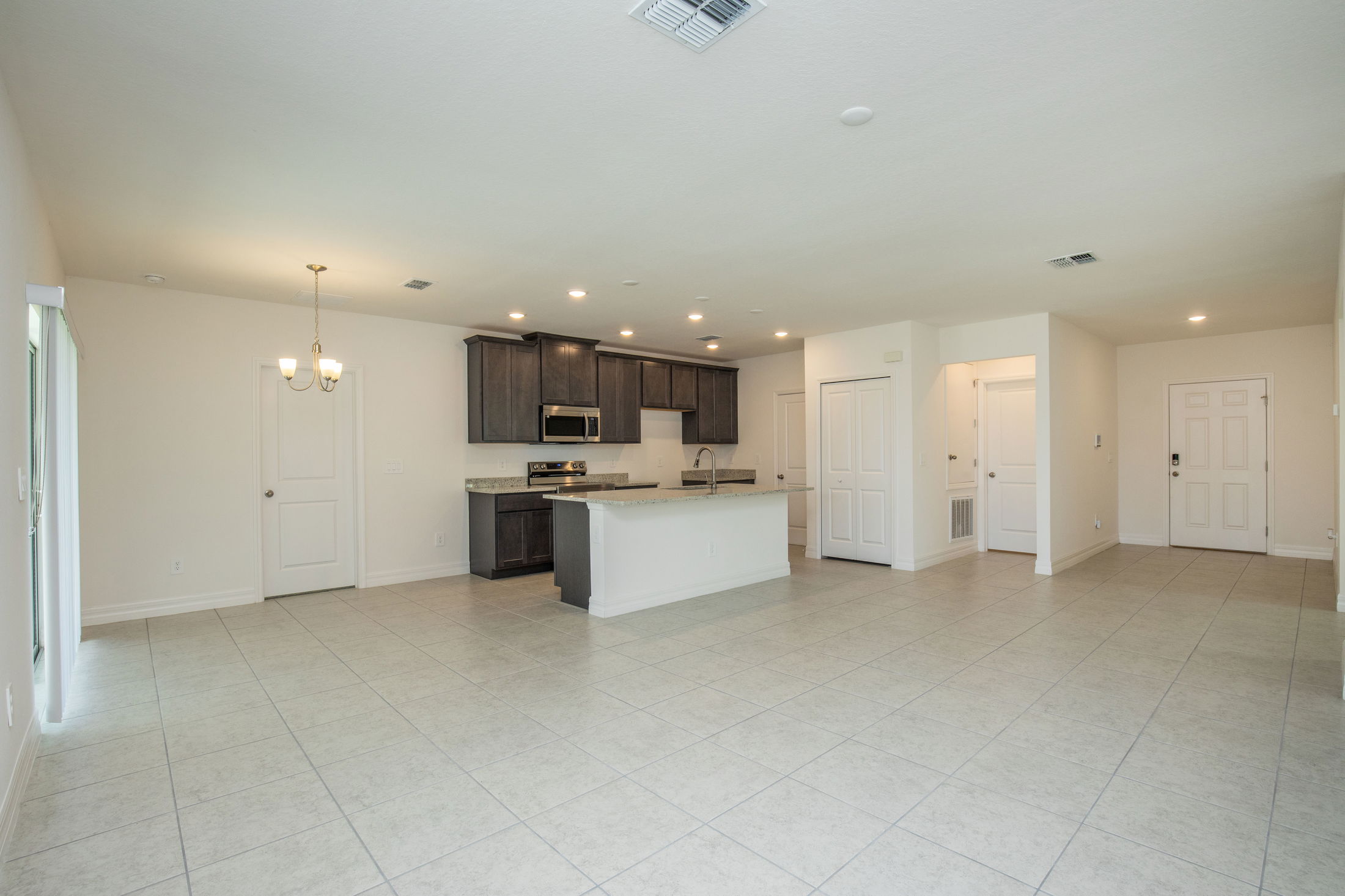 Spacious open-plan kitchen and living area with modern fixtures, tiled flooring, and ample natural light.