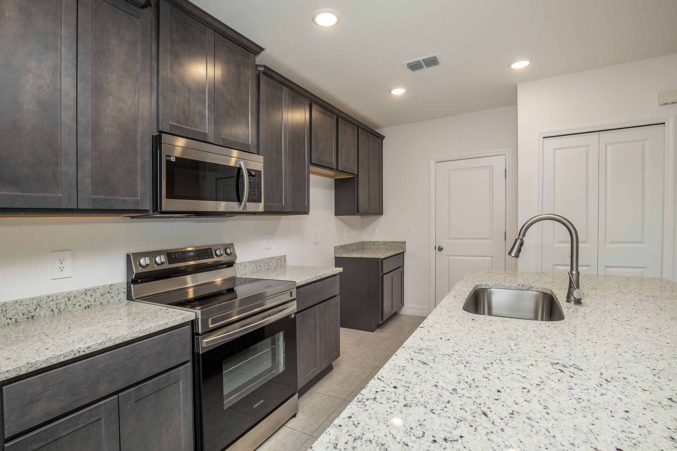 Modern kitchen with dark wood cabinets, stainless steel appliances, and granite countertops.