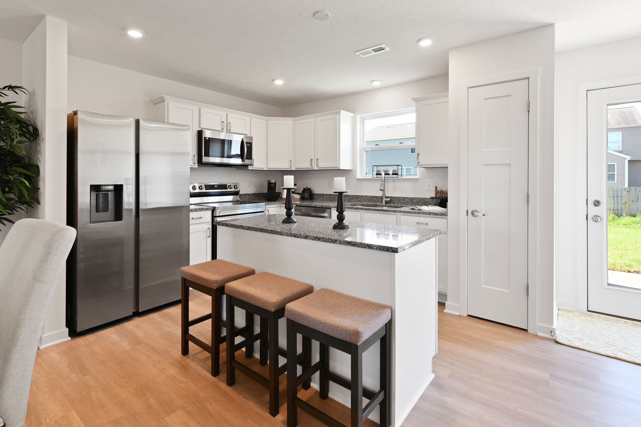 Modern kitchen with white cabinets, stainless steel appliances, and a granite island.
