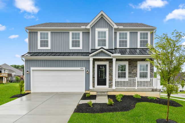 Two-story modern suburban house with gray siding, a front porch, and attached garage, surrounded by a well-maintained lawn under a blue sky.