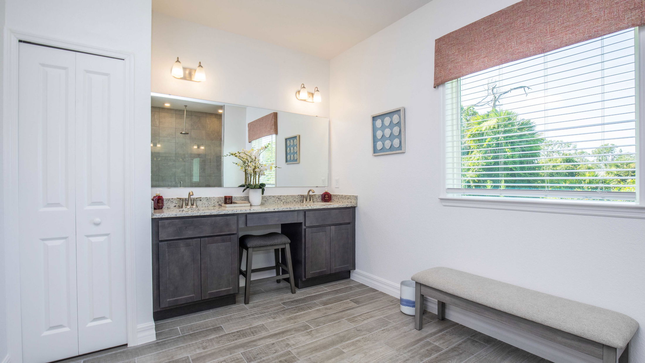 Modern bathroom with double vanity, granite countertop, large mirror, and tiled flooring.