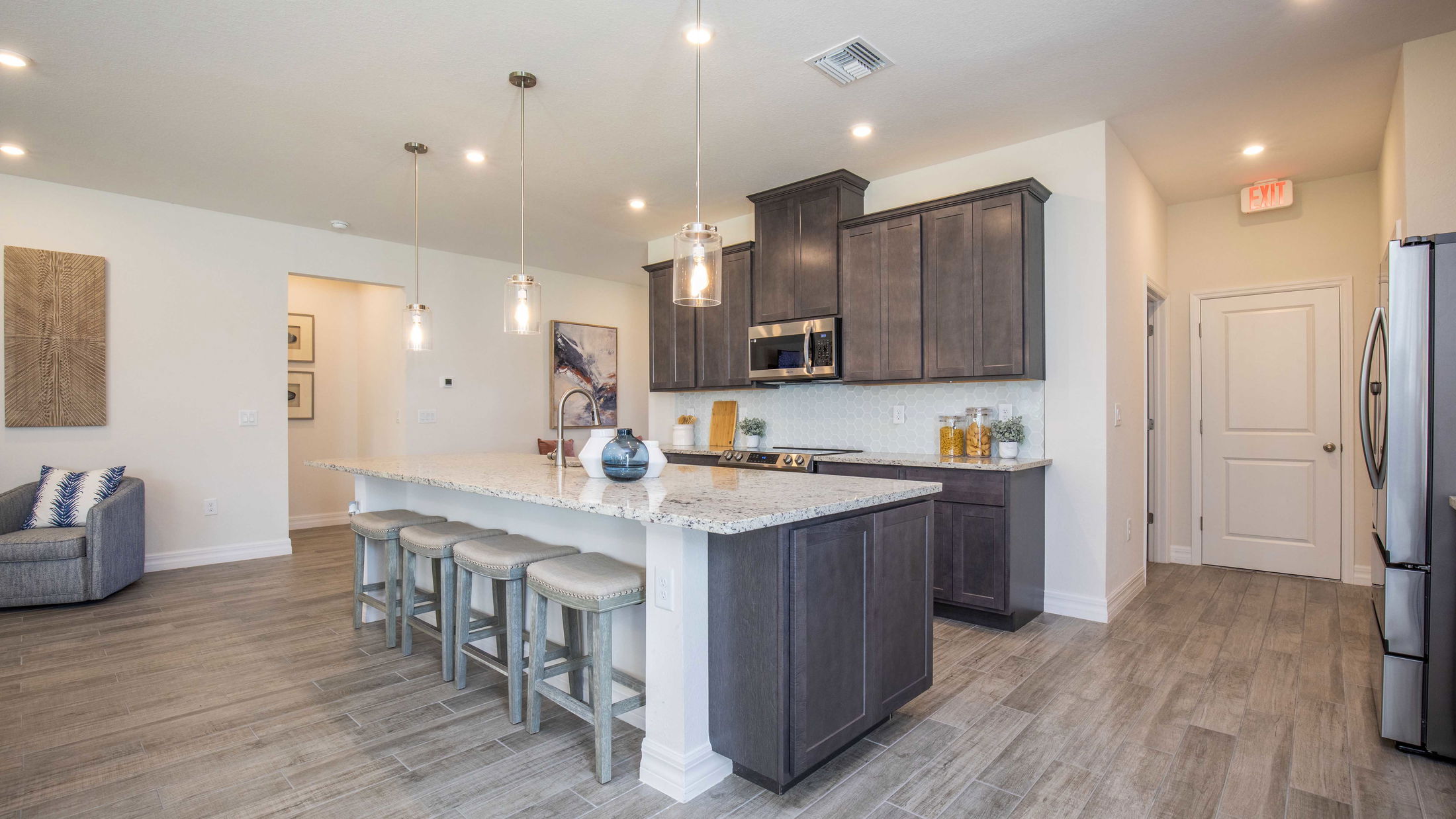 Modern kitchen with granite island, pendant lighting, and dark wood cabinets featuring neutral tones.