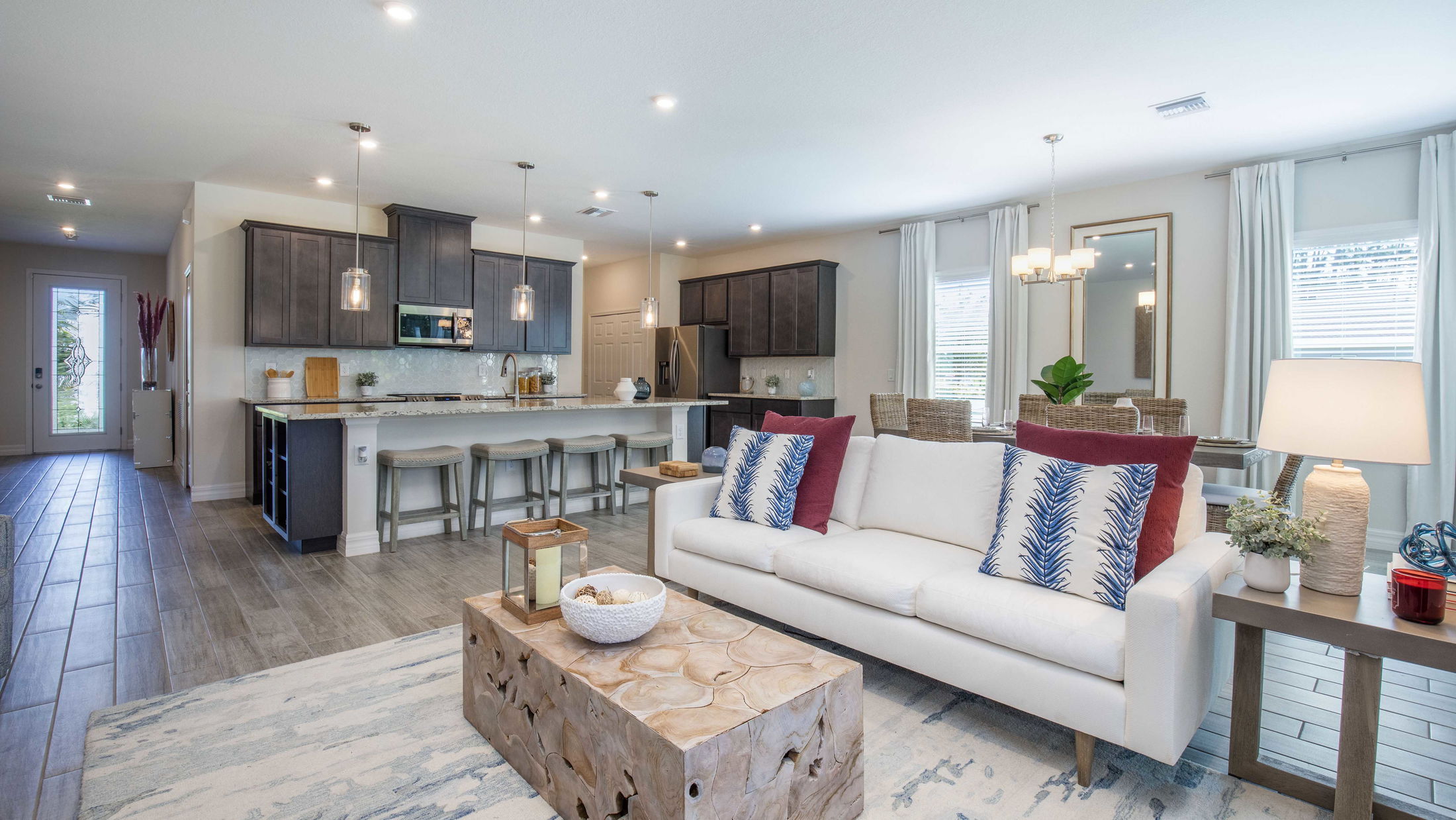 Modern open-concept living room and kitchen with stylish decor, featuring a white sofa, wooden coffee table, and contemporary light fixtures.
