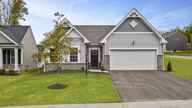 Cozy suburban house with a gray exterior and attached garage set on a neatly manicured lawn.