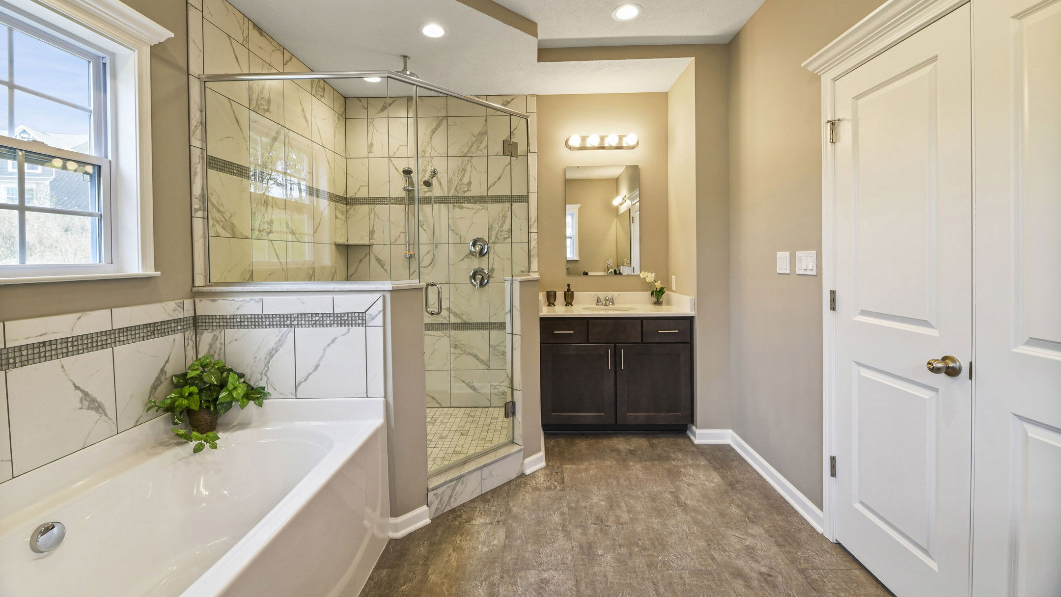 Modern bathroom with a glass-enclosed shower, bathtub, and dark wood vanity.