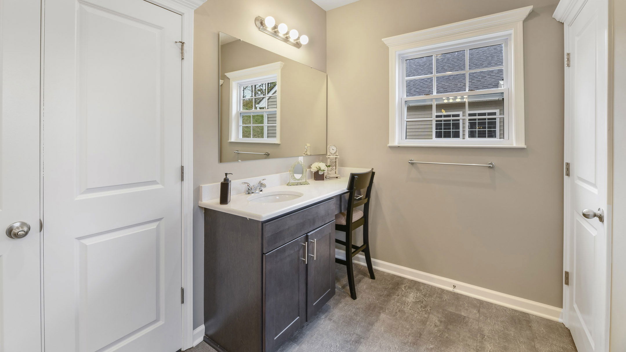 Modern bathroom with a dark wood vanity, large mirror, and natural light from a window.