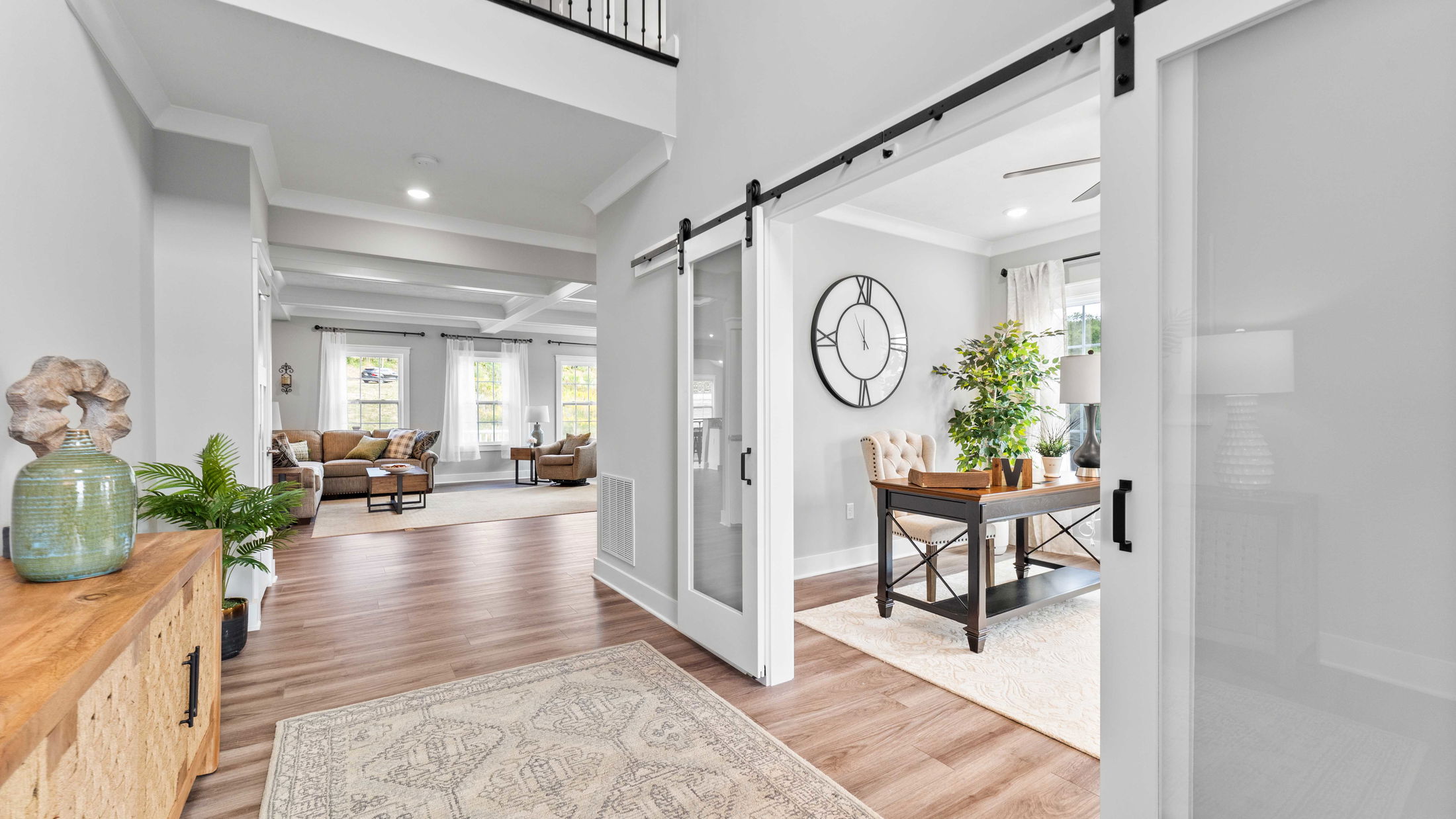Bright and modern living room with wooden floors, large wall clock, and stylish décor, featuring natural light through wide windows.