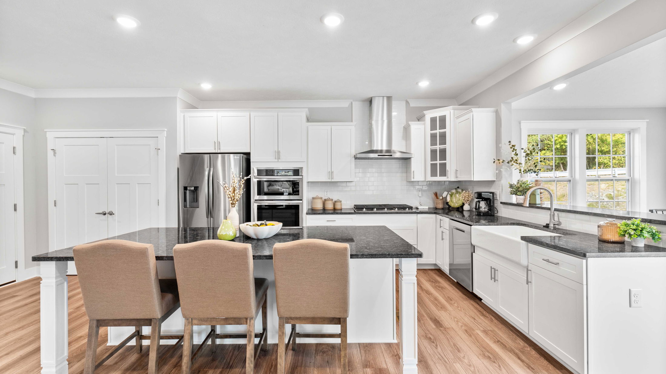 Modern kitchen with white cabinetry, black countertops, stainless steel appliances, and a central island with seating.