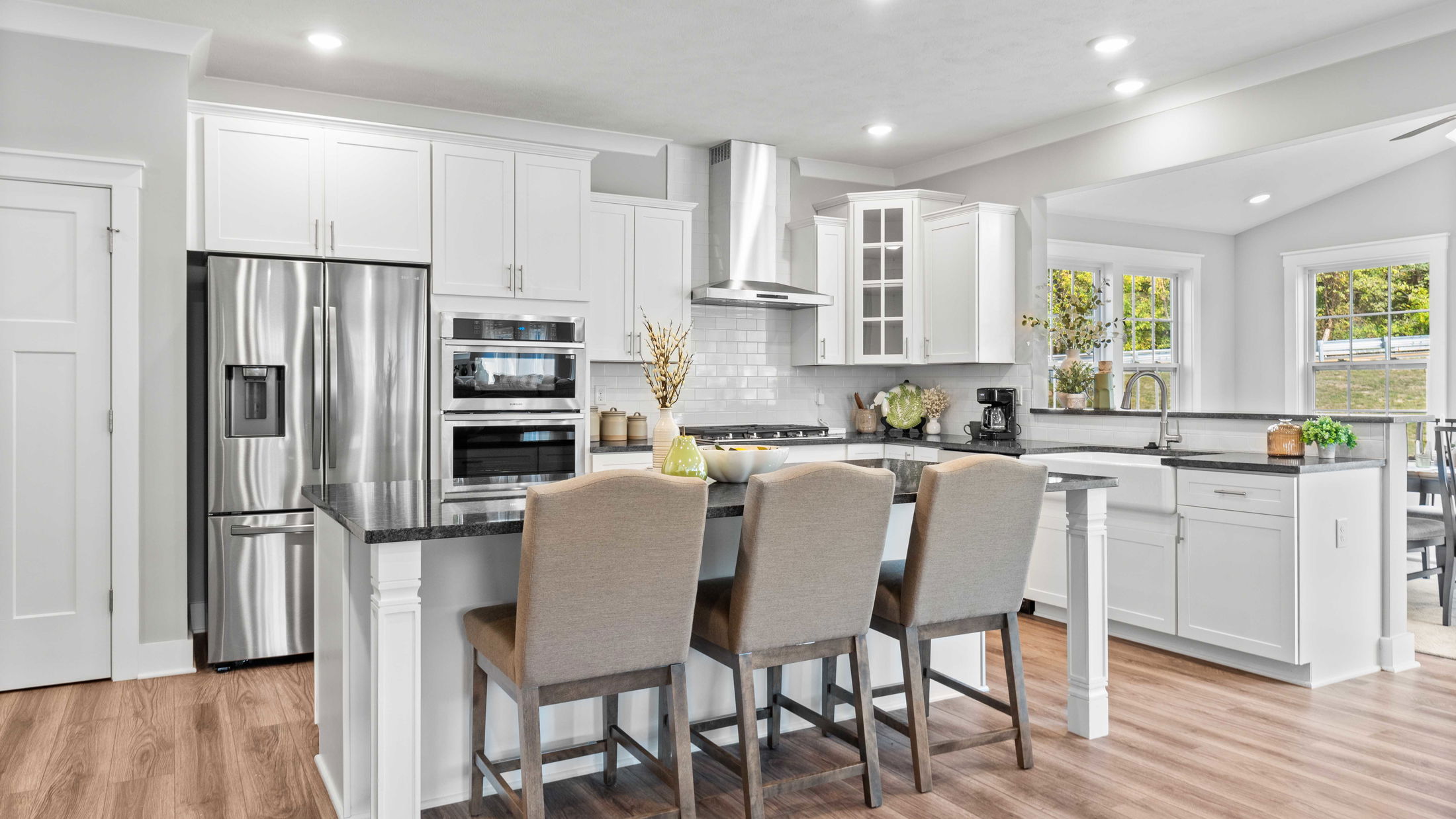 Modern kitchen with sleek stainless steel appliances, white cabinetry, and a central island with bar stools.