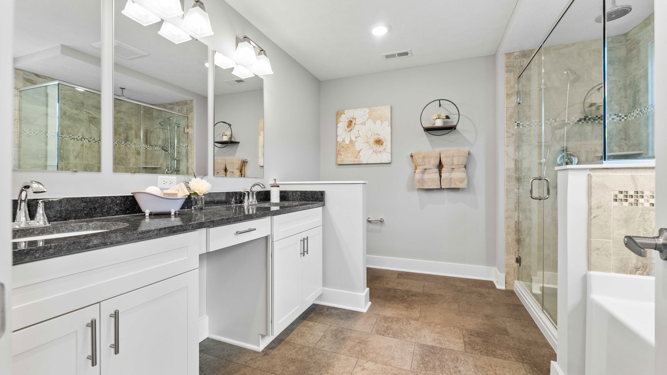 Modern bathroom with dual sinks, granite countertop, glass shower enclosure, and minimalist decor.