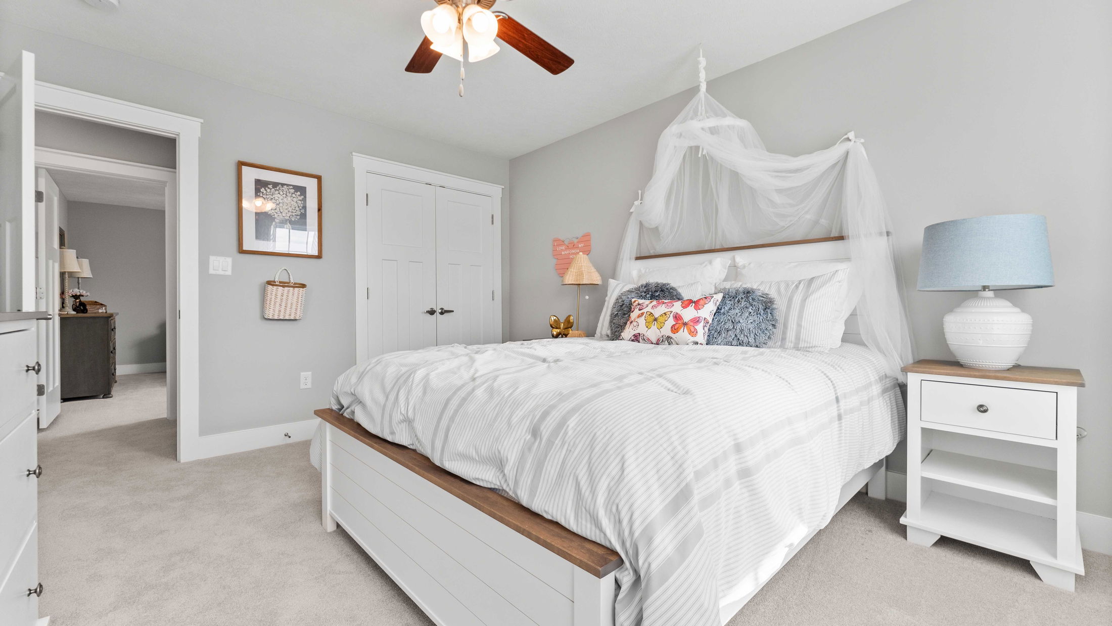 Bright and airy bedroom with a white bed, pastel decor, and cozy gray carpeting.