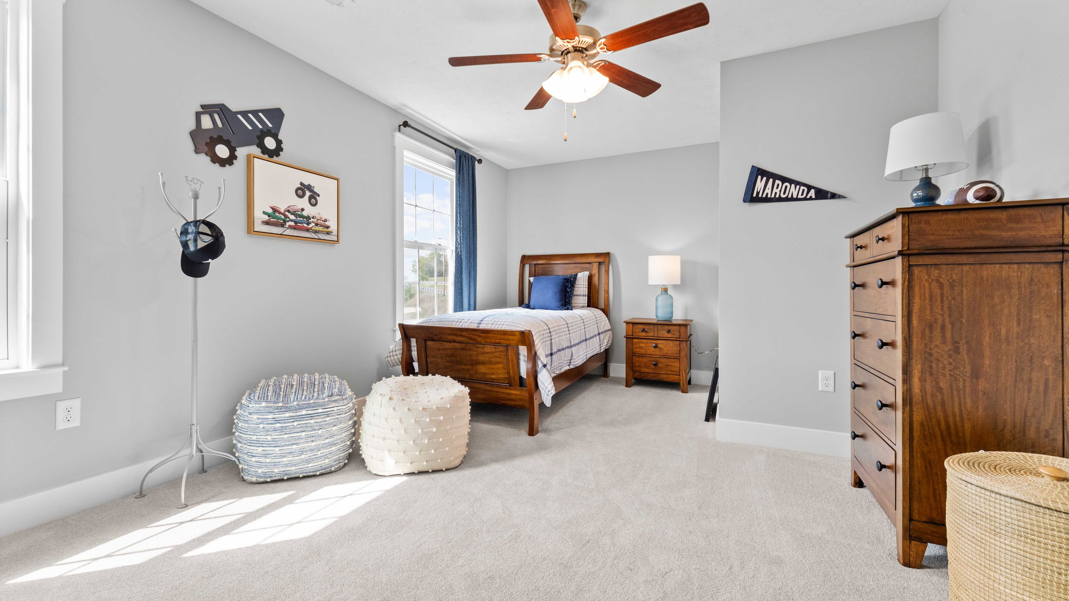 Modern, cozy bedroom with wooden furniture, gray walls, and decorative elements accentuating a boy's room theme.
