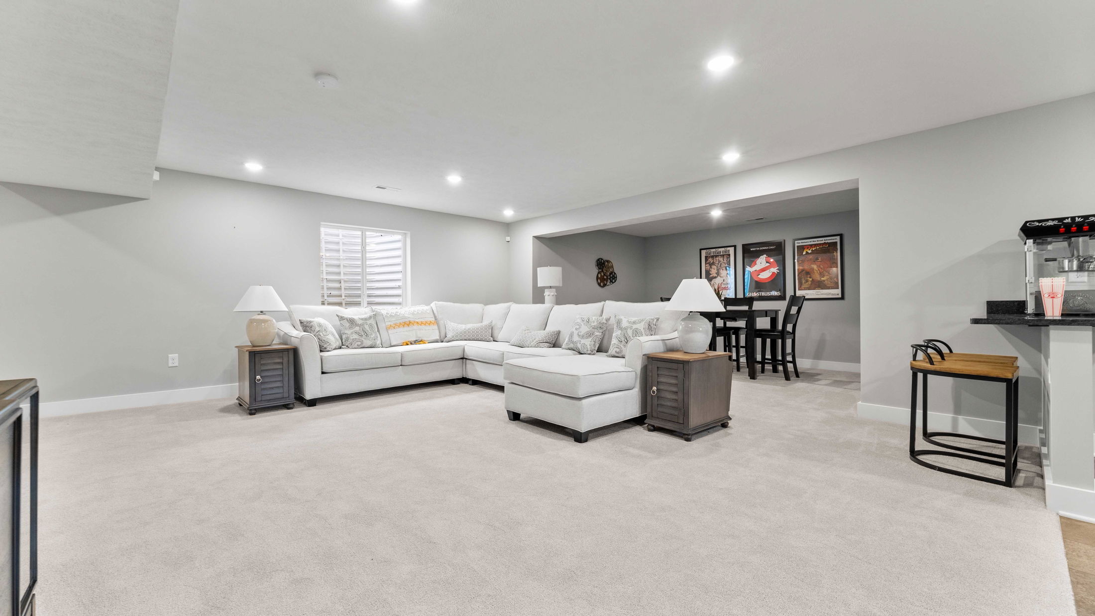 Spacious modern basement with a large white sectional sofa, stylish wall art, and a cozy entertainment area.