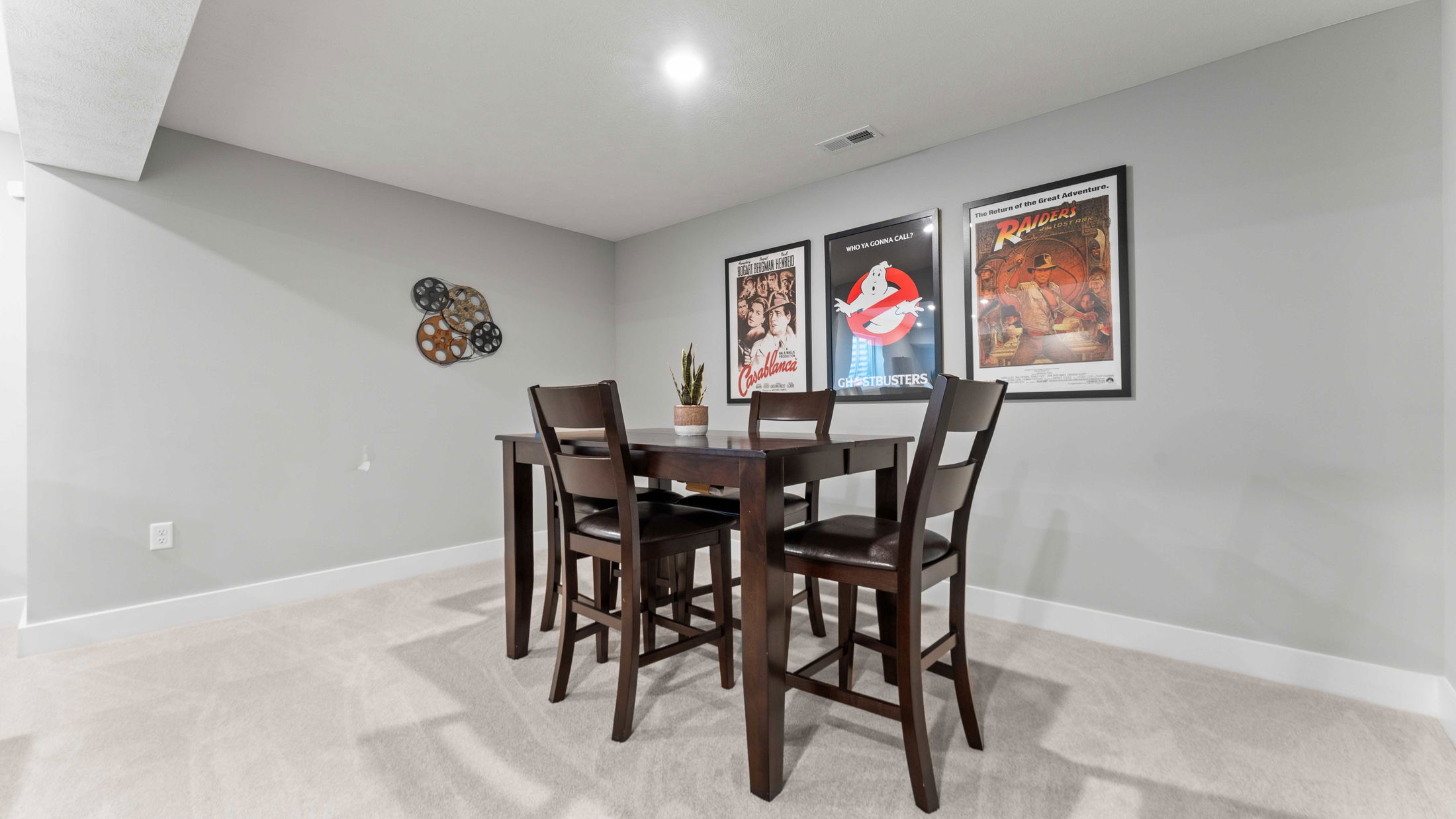 Modern home dining area with a wooden table and chairs, decorated with classic movie posters on gray walls.