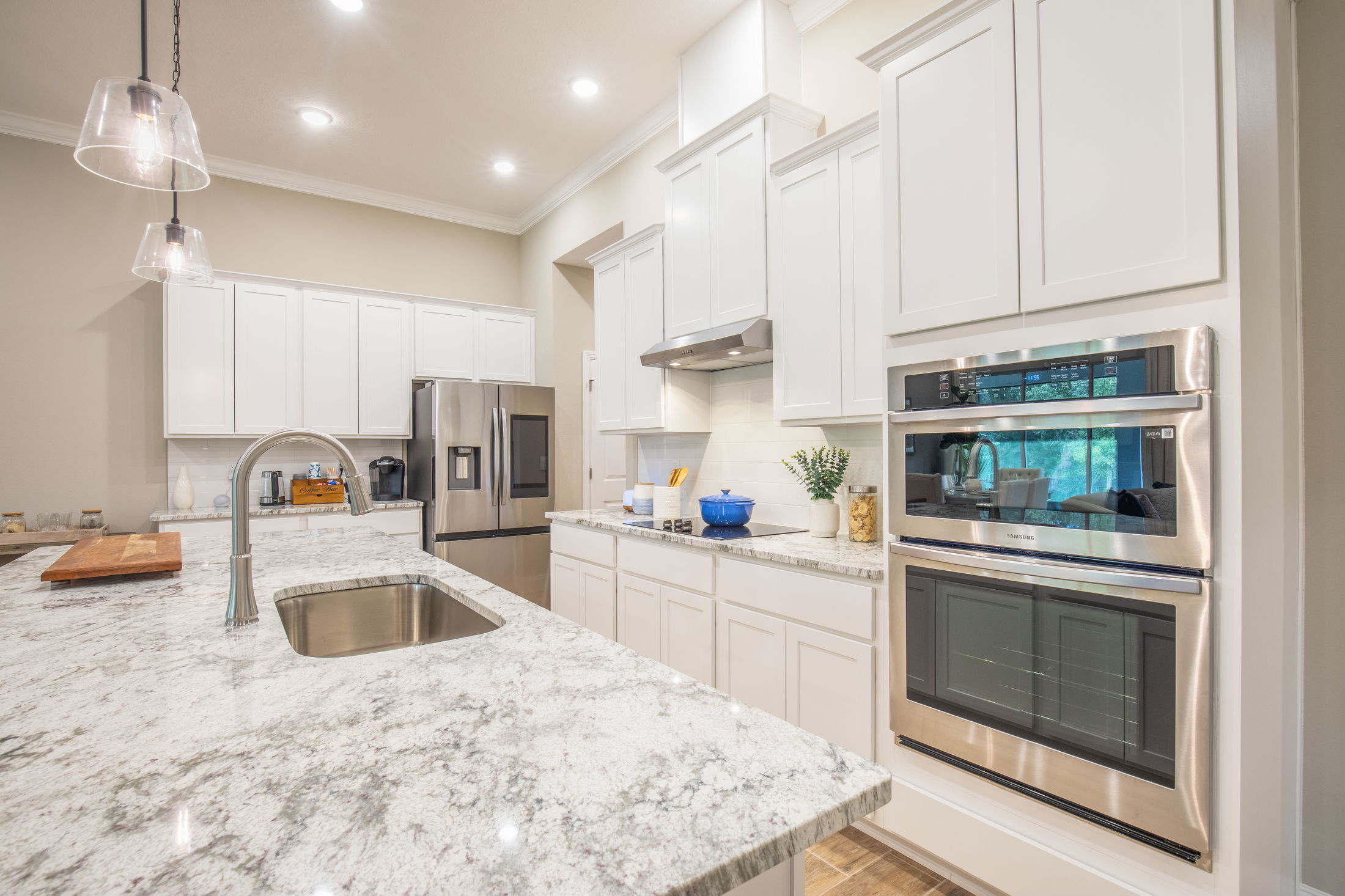 Modern kitchen featuring white cabinets, stainless steel appliances, and a polished granite island with a built-in sink.