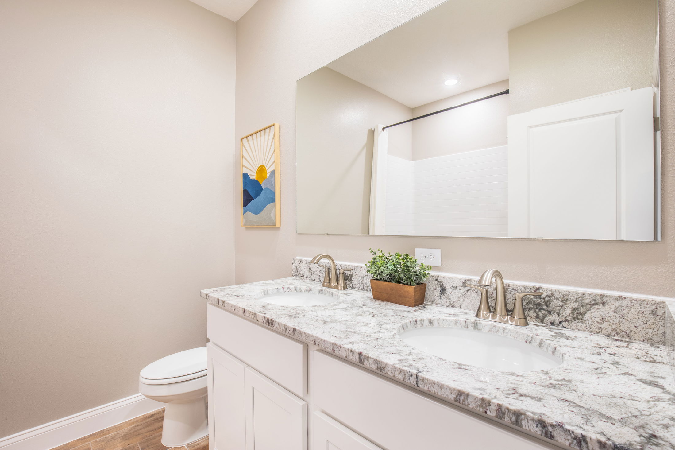 Modern bathroom with dual-sink granite countertop, sleek faucets, and minimalist decor for a stylish and functional space.
