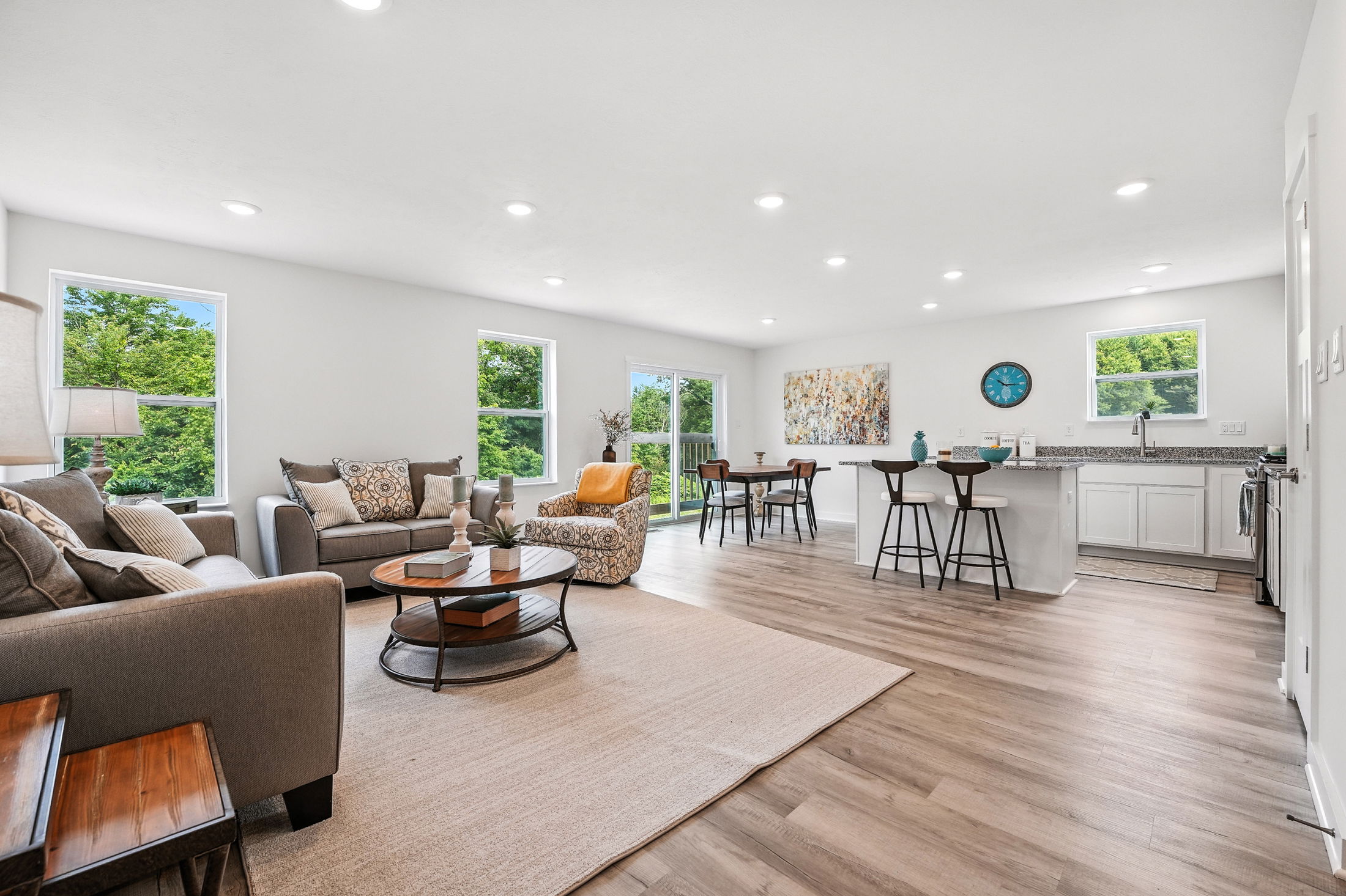 Bright and spacious open-concept living room and kitchen with modern decor, hardwood floors, and large windows.