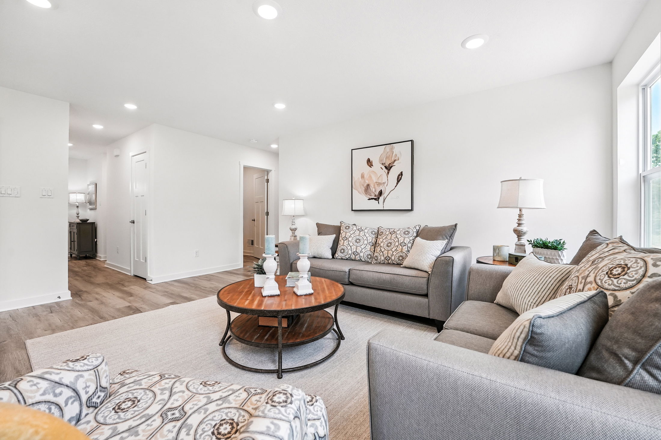 Modern living room with gray sofas, decorative pillows, wooden coffee table, and elegant wall art in a bright, minimalist space.