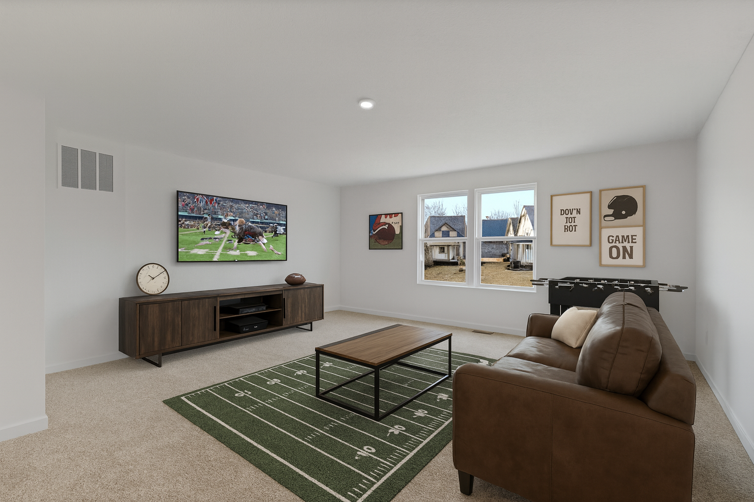 A cozy living room decorated in a sports theme features a wall-mounted TV displaying a football game, a brown sofa, wooden coffee table, football field-themed rug, and foosball table.