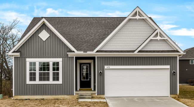 Modern grey single-story house with double garage and pitched roof under a clear blue sky.