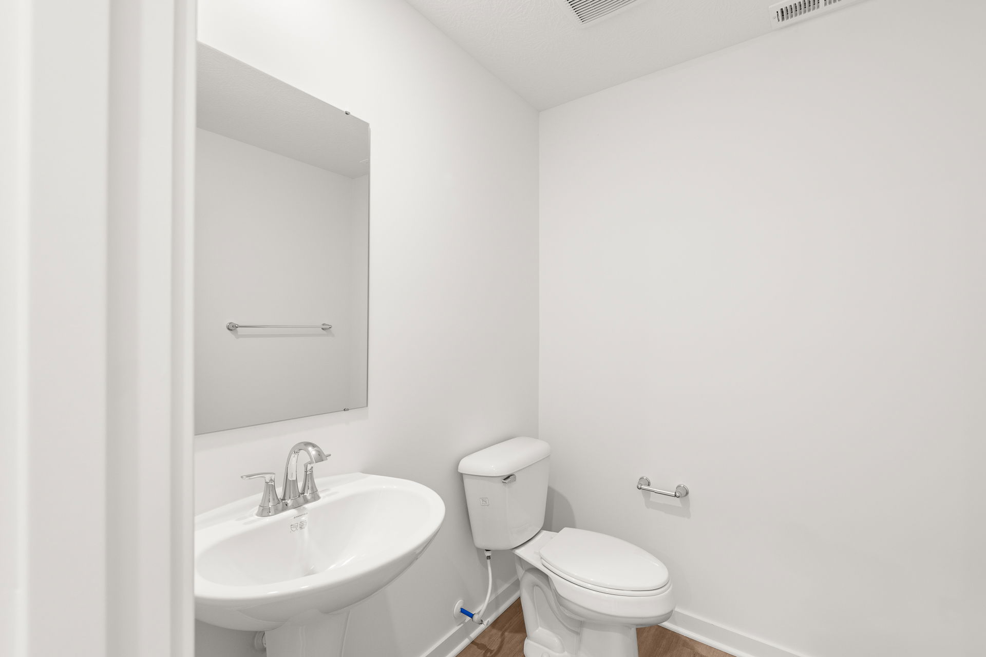 Modern minimalist bathroom with a white toilet and pedestal sink.