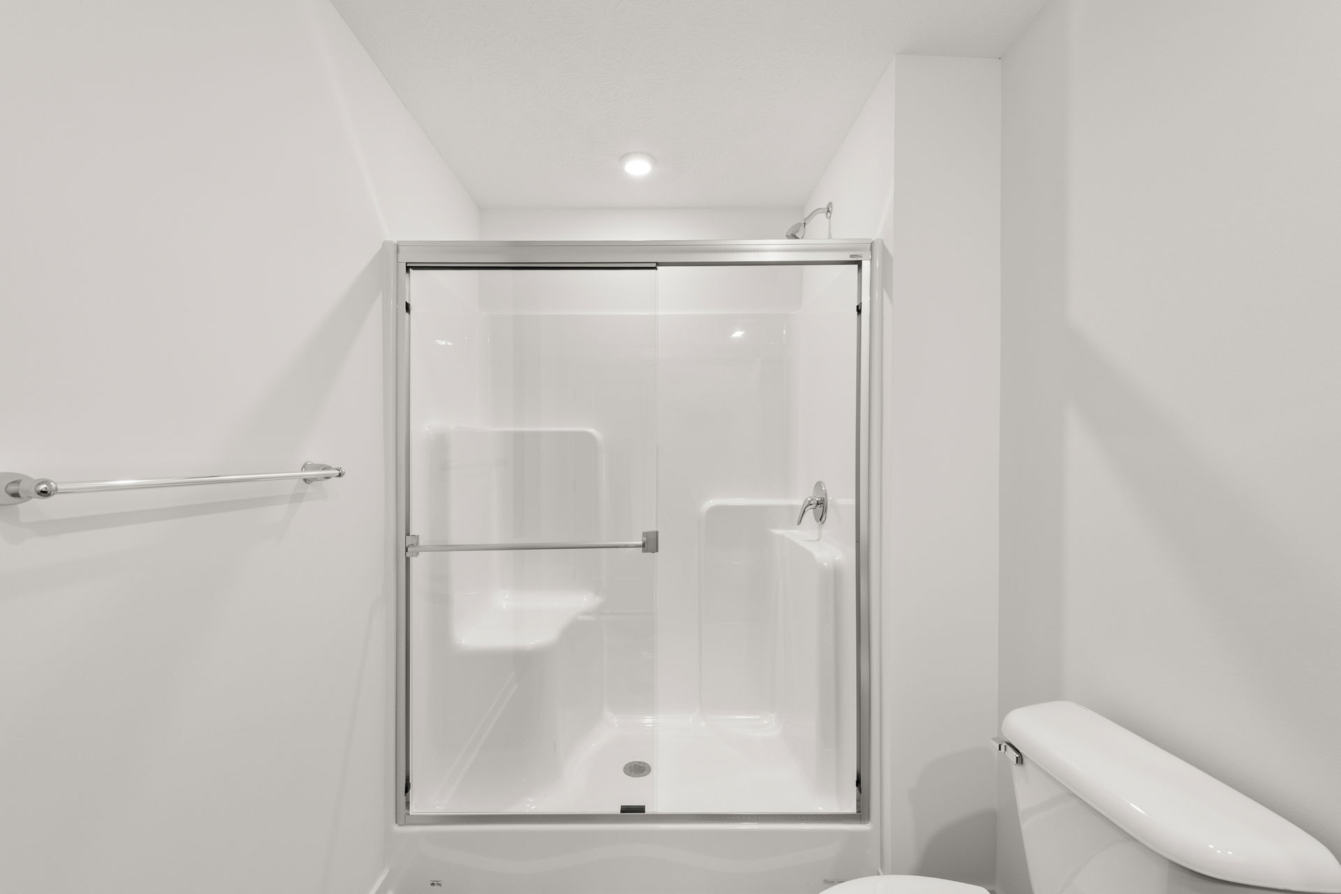 Modern white bathroom with a glass-enclosed shower and a toilet.