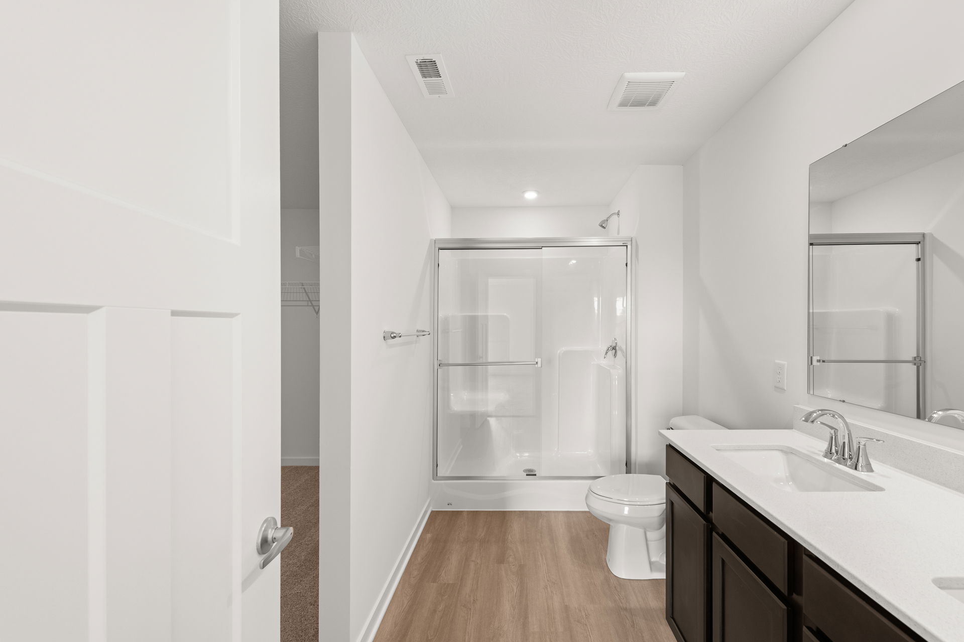 Modern bathroom featuring a glass shower, sleek vanity with dual sinks, and neutral color scheme.