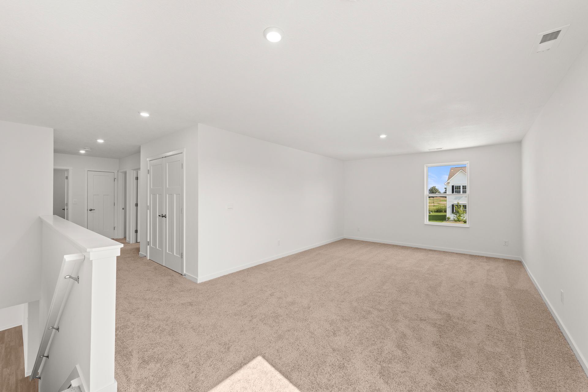 Spacious and well-lit living room with plush carpeting and a large window showcasing a beautiful outdoor view.