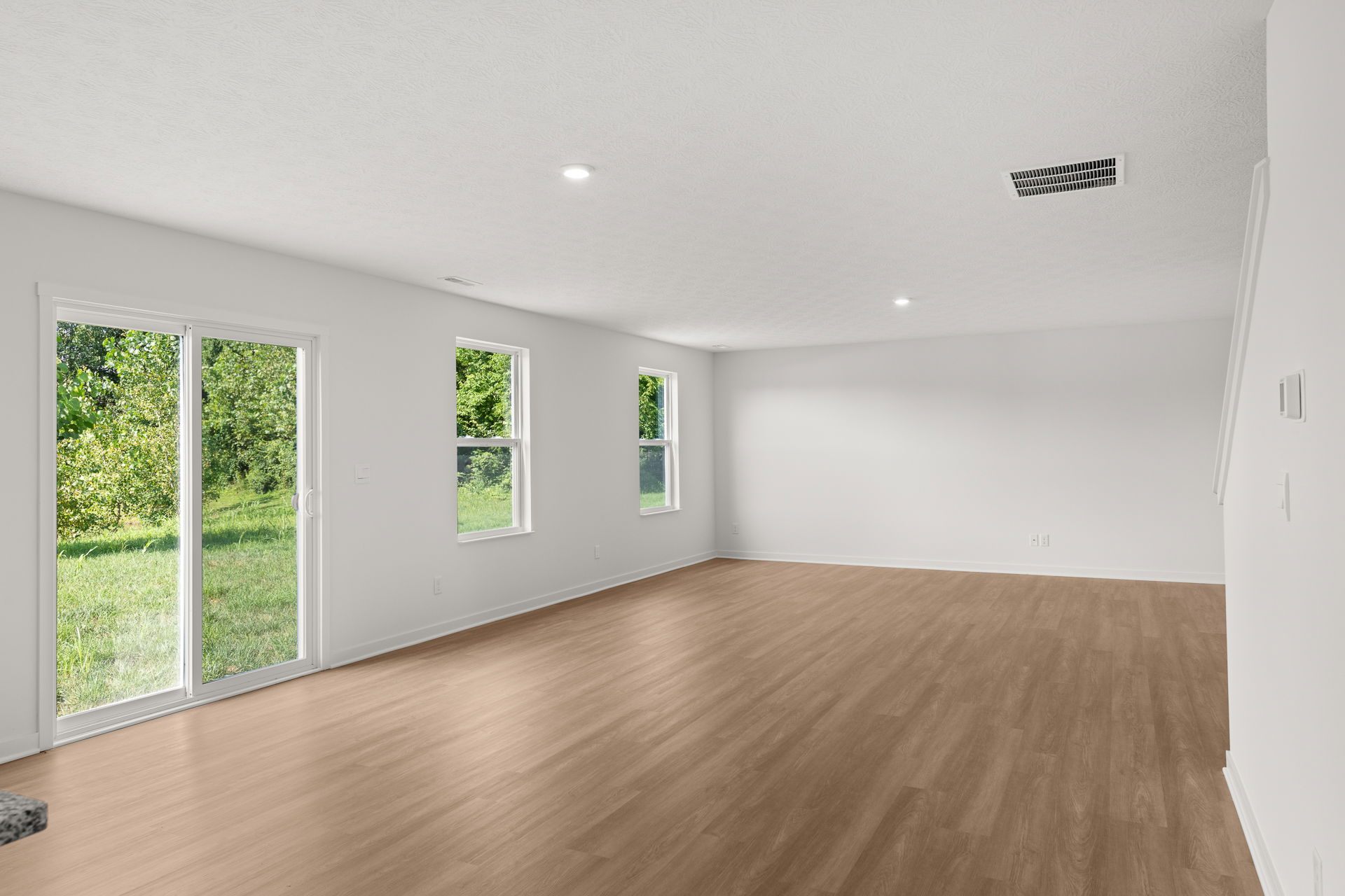 Bright and spacious living room with large windows and wood laminate flooring.