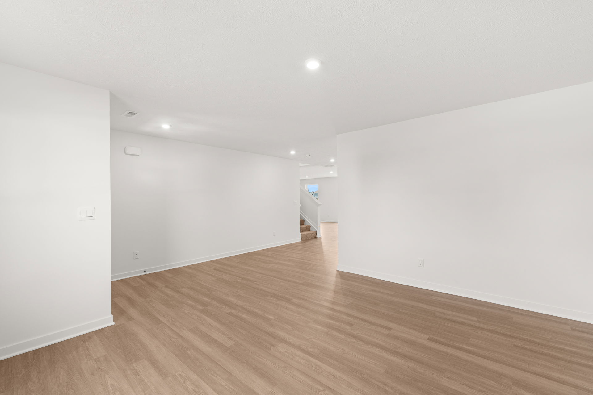 Spacious, modern living room with light wood flooring and neutral-colored walls.