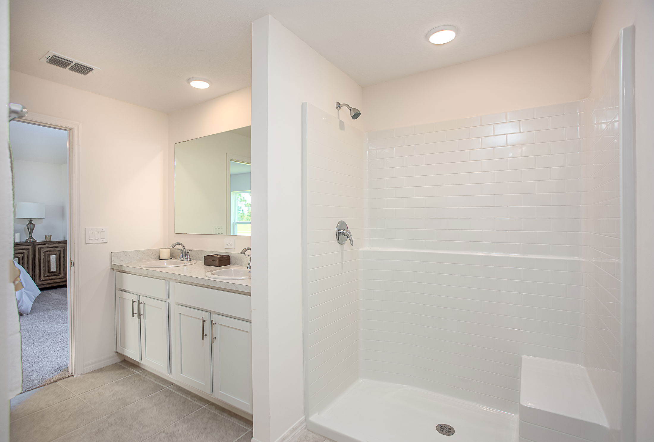 Modern bathroom with white cabinetry, dual sinks, and a spacious walk-in shower.