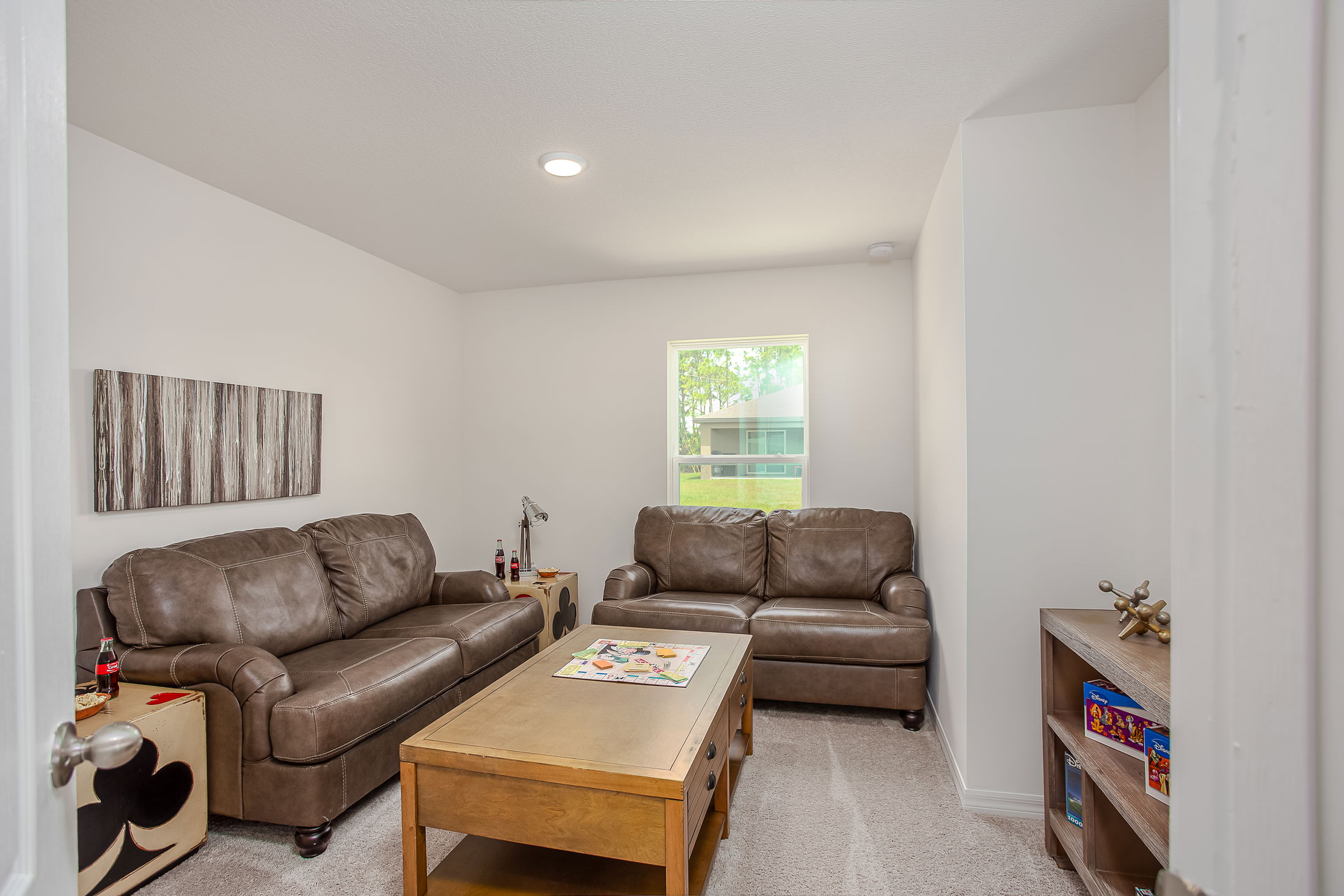 Cozy living room featuring brown leather sofas, a wooden coffee table, and natural light through a window.