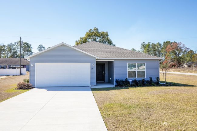 Single-story modern house with a gray exterior, two-car garage, and well-maintained front lawn under a clear blue sky.
