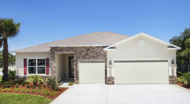 Stylish single-story suburban home with stone accents, white garage doors, and a manicured front lawn under a clear blue sky.