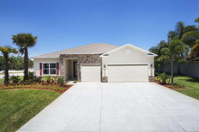 Modern single-story home with a spacious two-car garage, palm trees, and a well-manicured lawn.