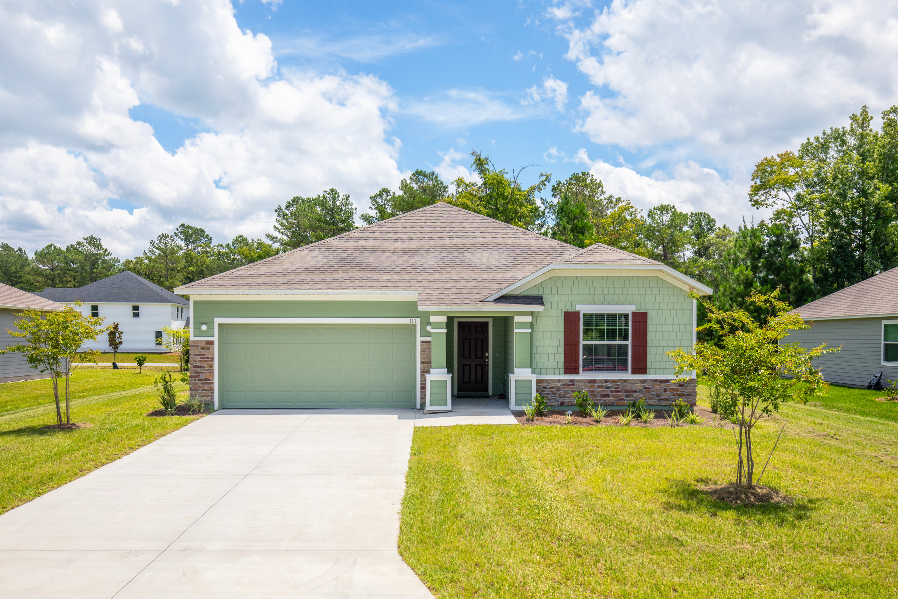 Suburban single-story green house with attached garage and well-maintained lawn.