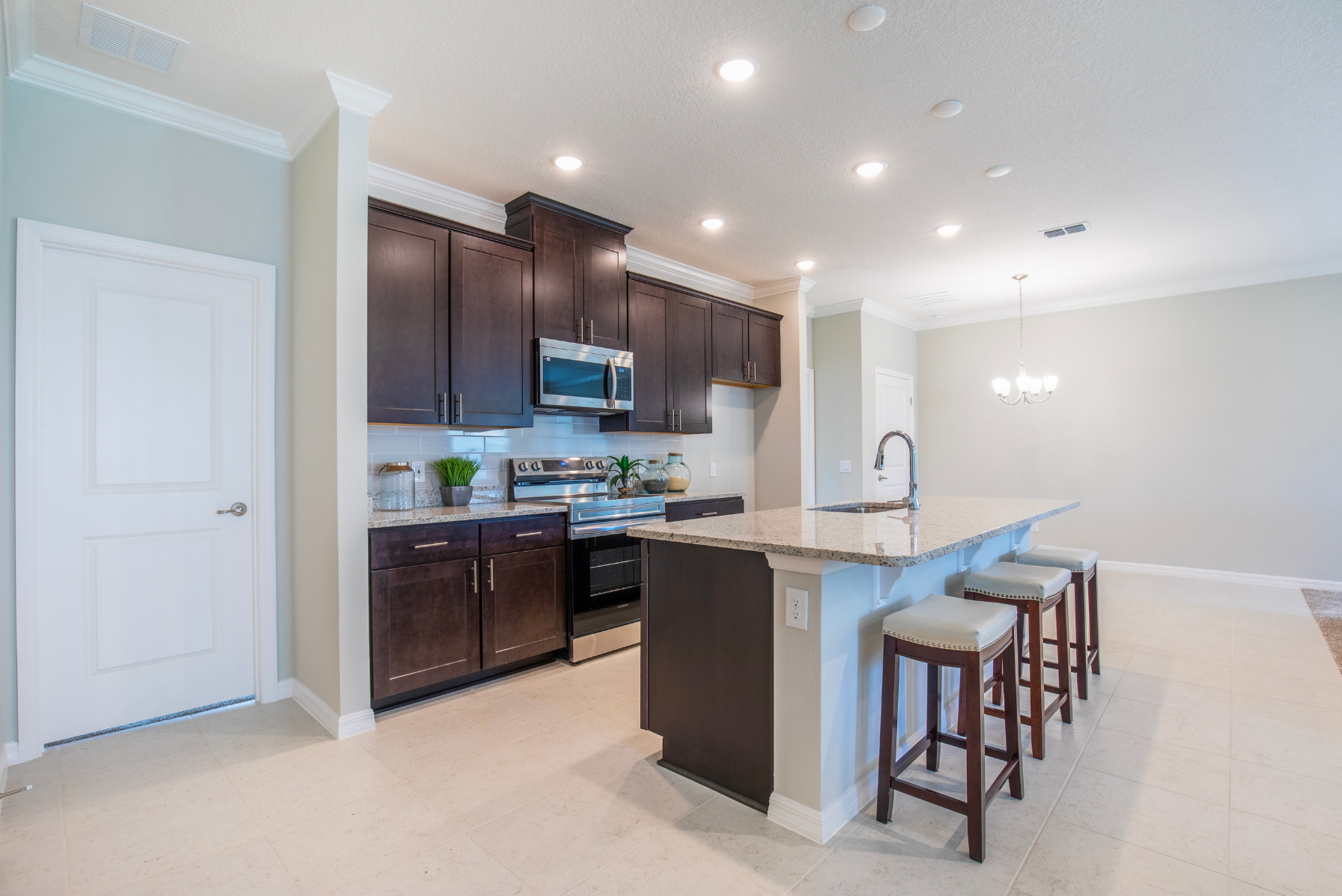 Modern kitchen with dark wood cabinets, stainless steel appliances, and a granite island with seating.