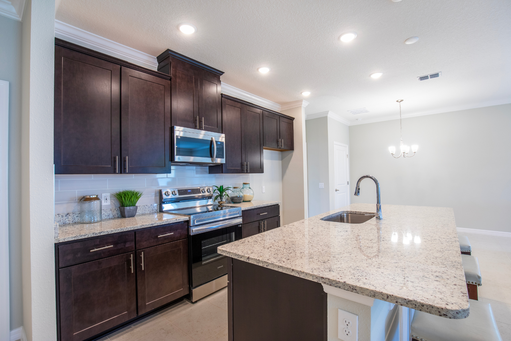 Modern kitchen with dark wood cabinets, granite countertops, stainless steel appliances, and a breakfast bar.