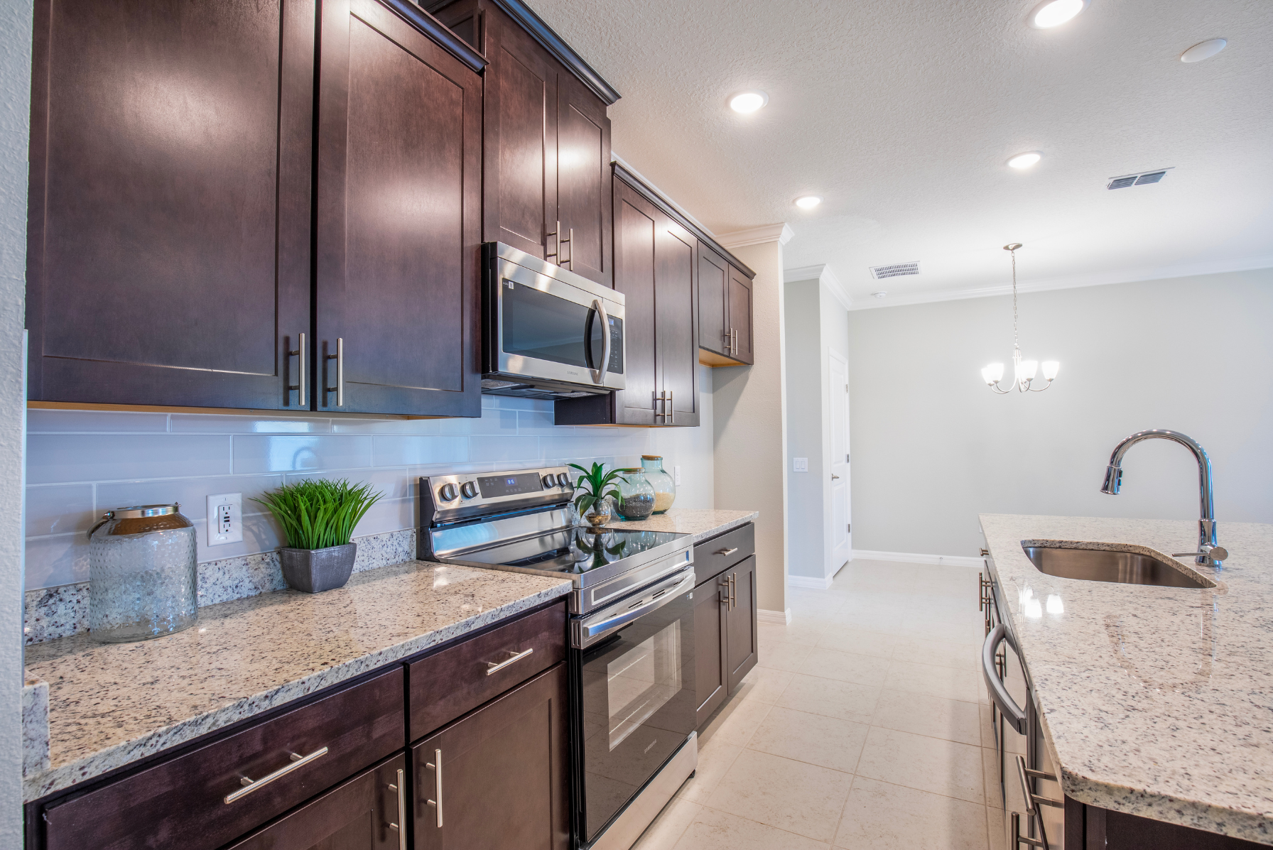 Modern kitchen with granite countertops, stainless steel appliances, and dark wood cabinetry under bright ceiling lights.