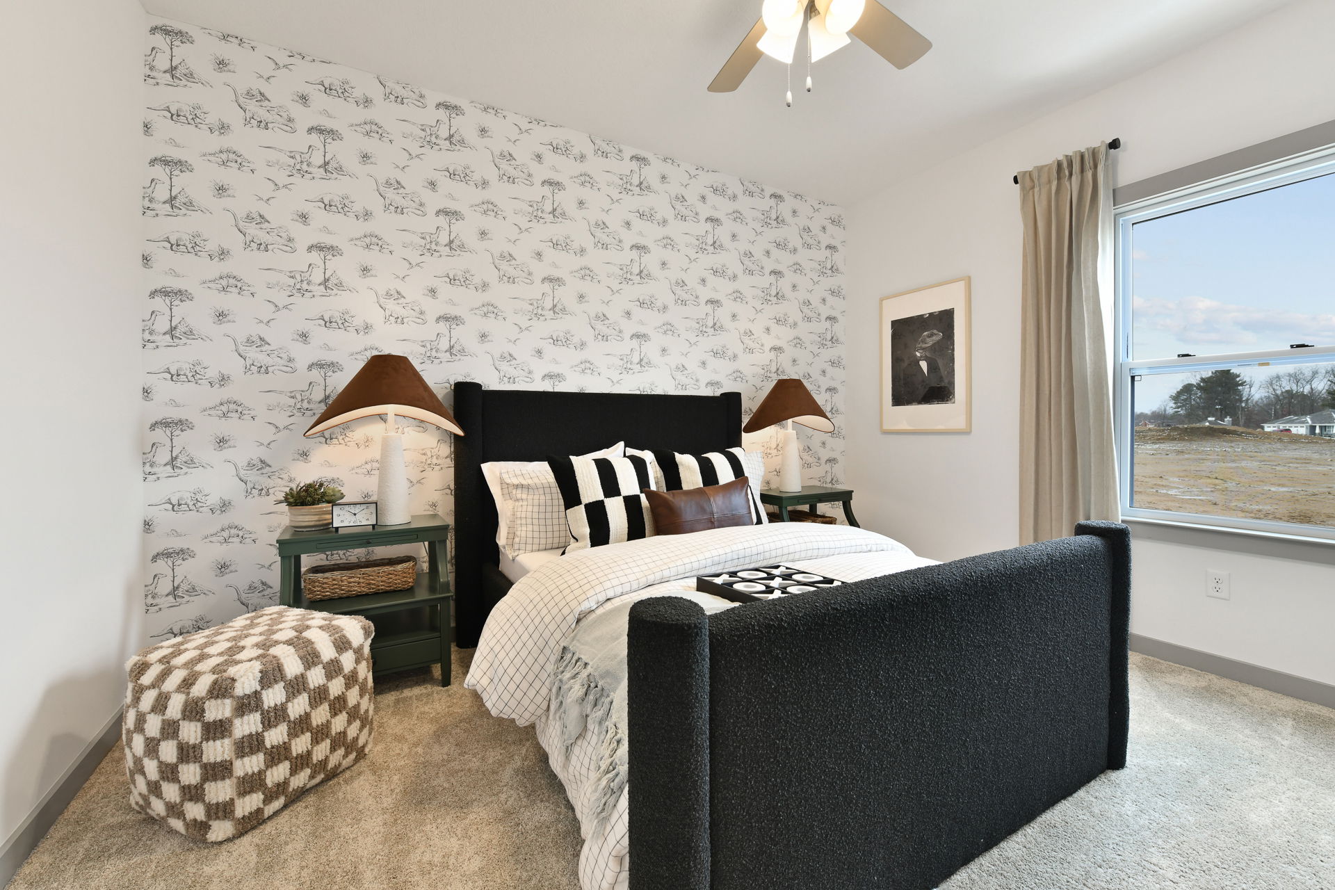 Cozy bedroom with a black upholstered bed, patterned wall, and large window overlooking a scenic view.