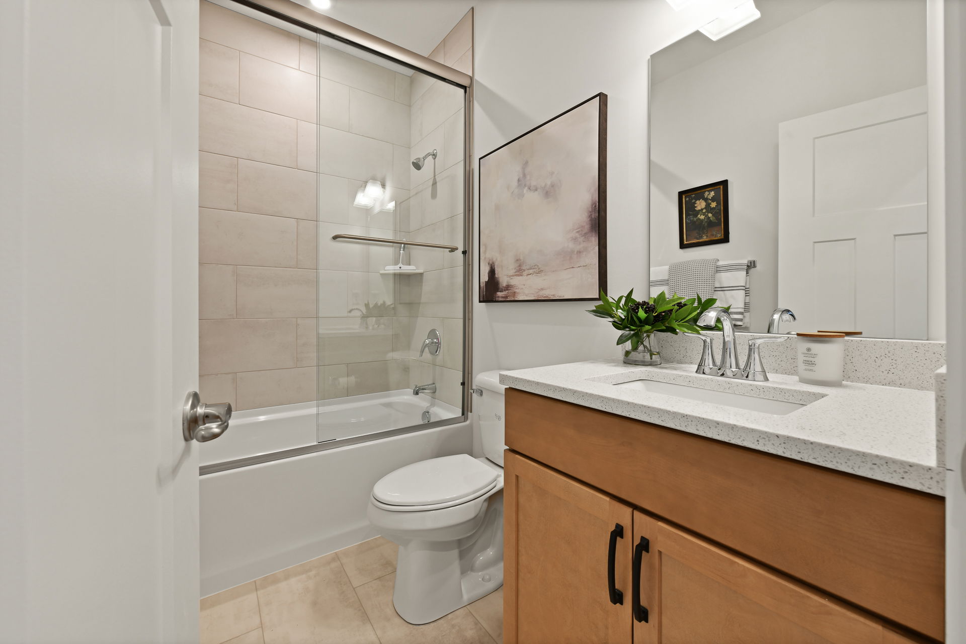 Modern bathroom with a glass-enclosed bathtub, wooden vanity, and minimalist decor.